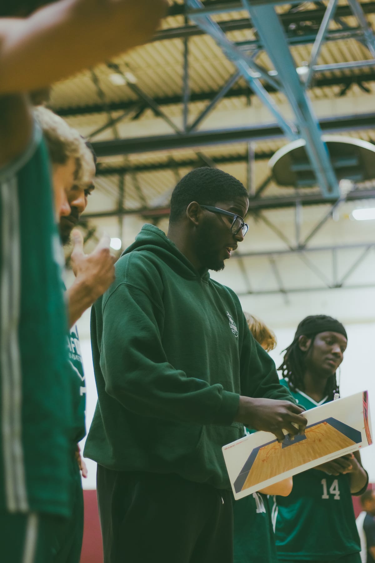Ahmed Salia Touré dirigeant un entraînement de La Forge Basketball, tableau tactique en main